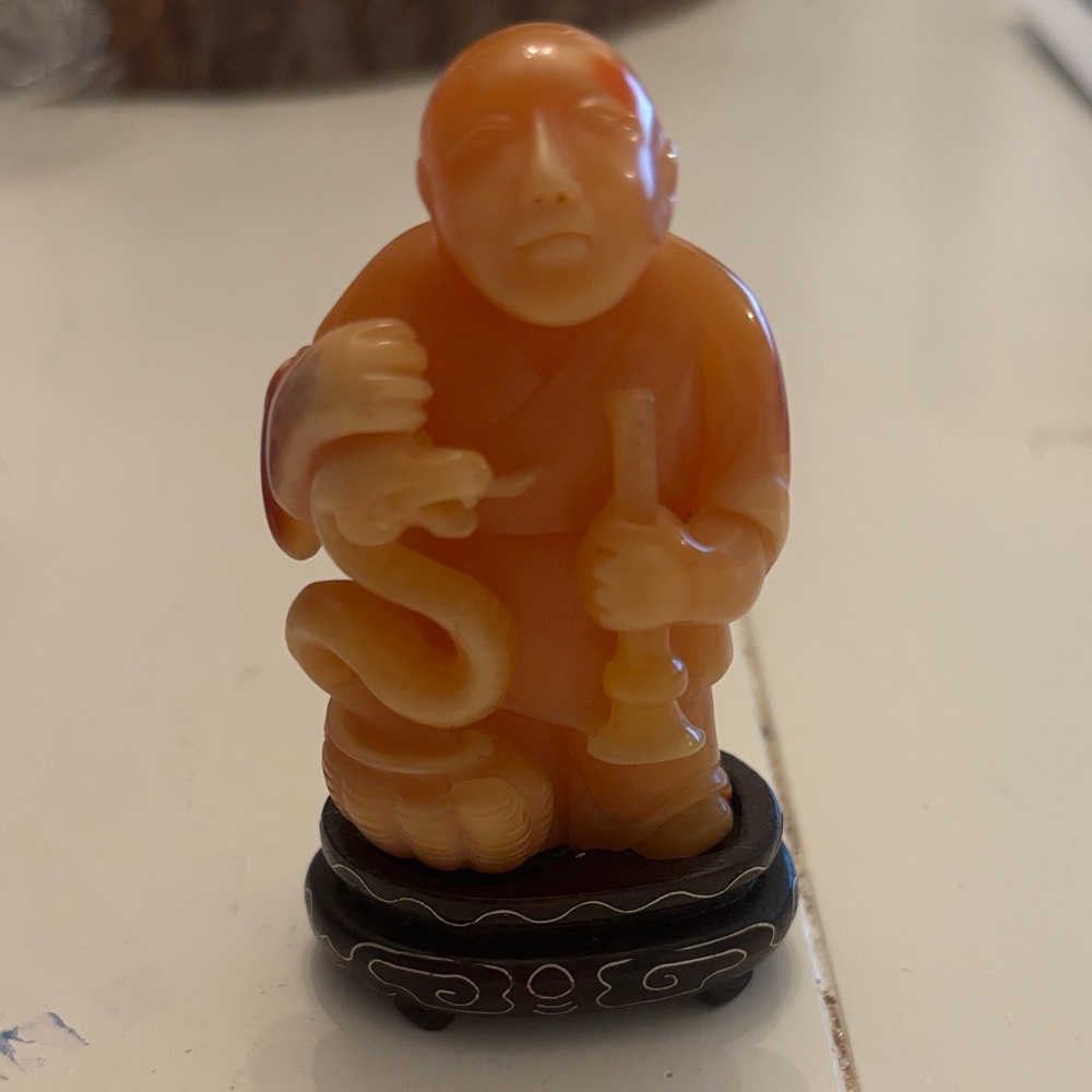 Chinese hard-stone carving of a monk with serpent, on stand, mid- 20 century